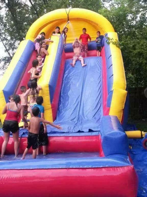 Kids playing on a water slide bounce house rental