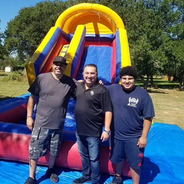 The Bouncers R Us team standing in front of one of their bounce house rentals